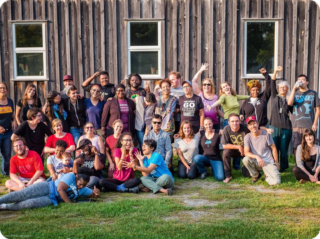 Group posing cheerfully outside wooden building