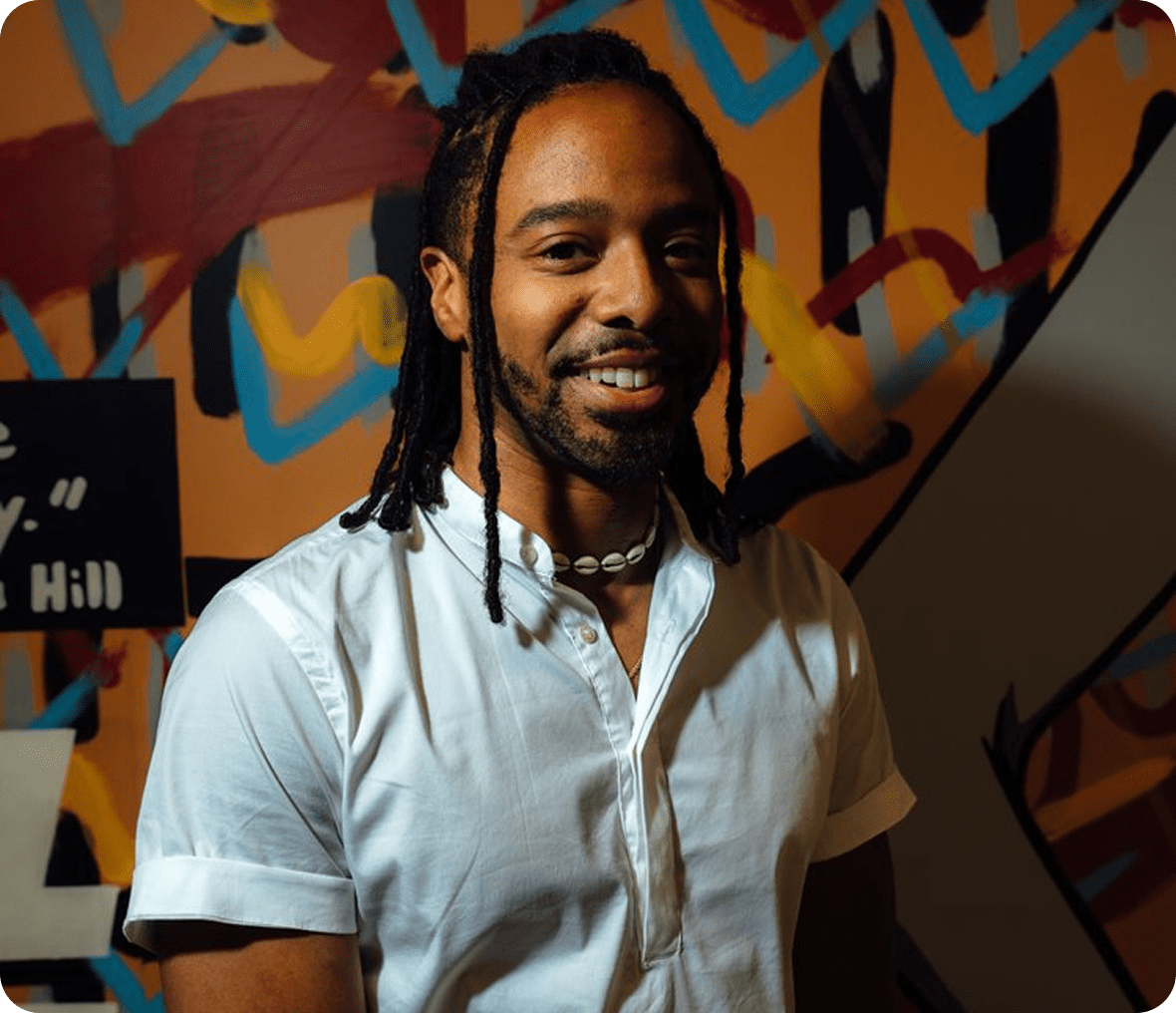 Smiling individual with dreadlocks and necklace