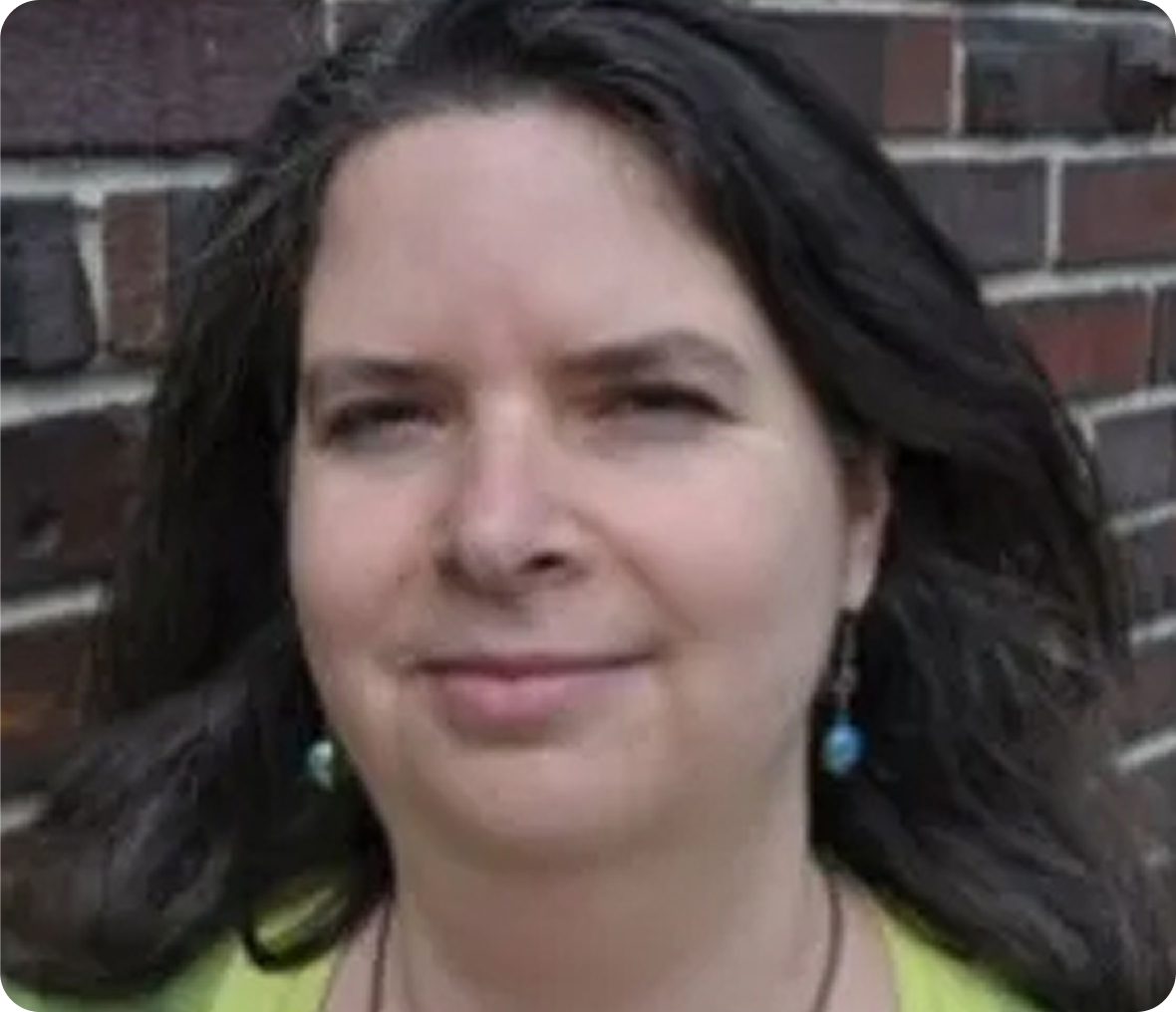 Woman smiling against brick wall background.
