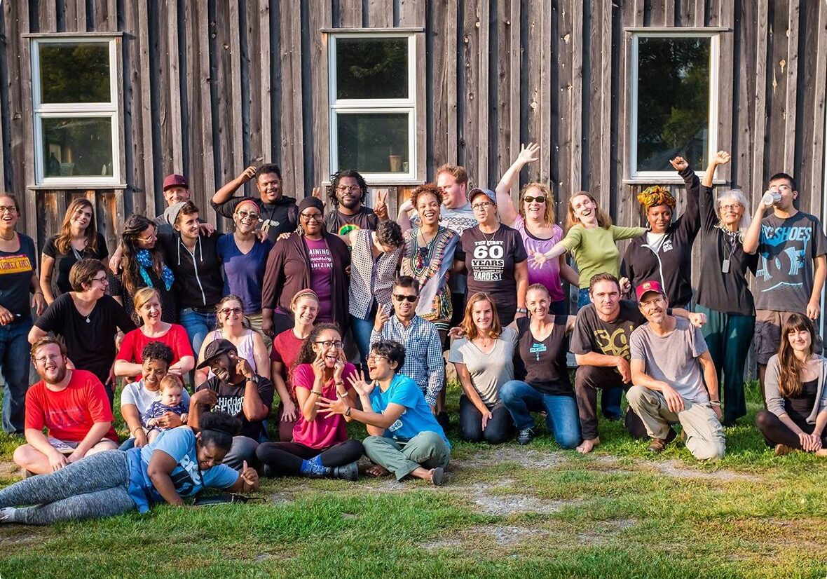 Group posing cheerfully outside wooden building